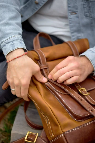 Manliga händer som tar läder brun handgjord ryggsäck på promenad, närbild foto. — Stockfoto