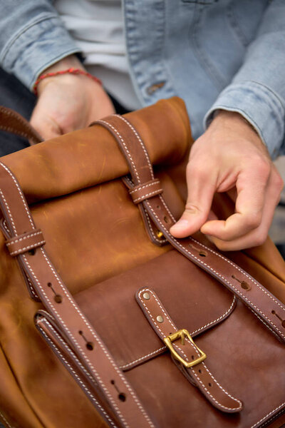 Мужчина берет кожу коричневый рюкзак ручной работы на прогулке, крупным планом фото.