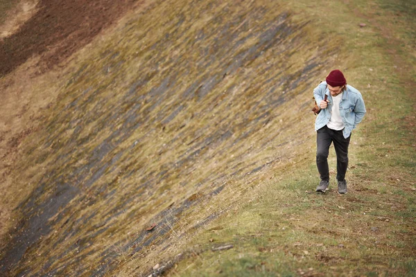 Hipster cestovatel v ležérní oblečení procházky v přírodě, výstup na kopec, člověk chodí sebevědomě. — Stock fotografie