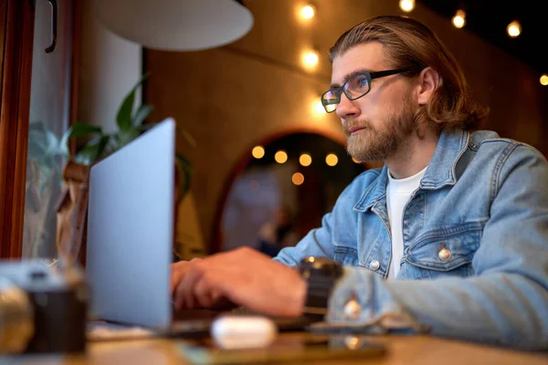 Baard man zitten aan cafe tafel met laptop, freelancer genieten van werken op afstand — Stockfoto