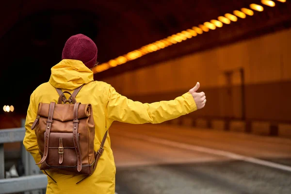 Vy från tillbaka på ung man liftar runt i landet, försöker fånga passerande bil — Stockfoto