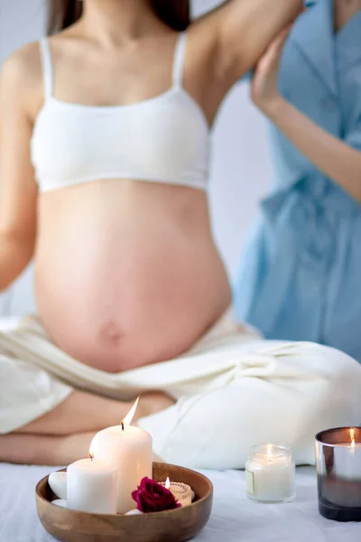 Крупним планом фото свічок у спа-салоні, вагітна жінка отримує масаж на задньому плані — стокове фото
