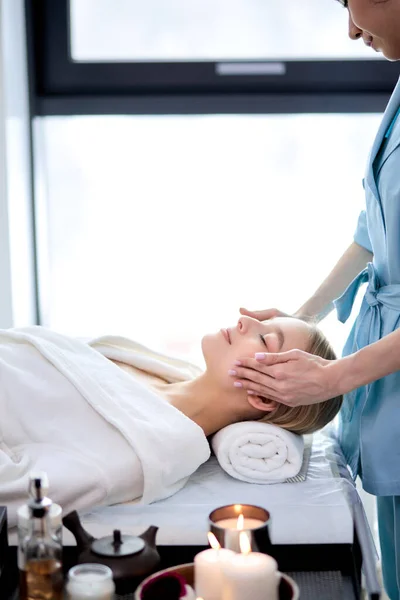 Señora acostada con los ojos cerrados y tener la cara o la cabeza de masaje en el spa por profesional — Foto de Stock