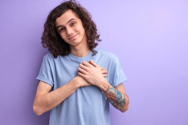 Kıvırcık saçlı hoş bir adam ellerini göğsünde tutuyor, erkek her şey için minnettar.