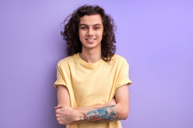 Sakin gülümseyen erkek, kollarını kavuşturmuş, kameraya özgüvenli bir şekilde bakıyor, boşluğu kopyalıyor.