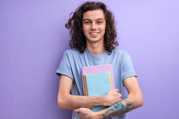 Uzun kıvırcık saçlı, elinde kitap tutan, üniversiteye giden iyimser bir erkeğin portresi. — Stok fotoğraf
