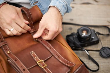 Kesilmiş fotoğrafçı erkek deri sırt çantasından fotoğraf makinesi alıyor.