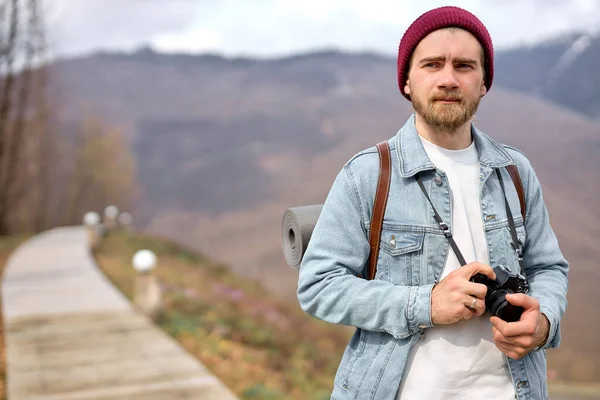 Aktivní zdravý běloch s batohem a kamerou kráčí ke vzdálené hoře — Stock fotografie