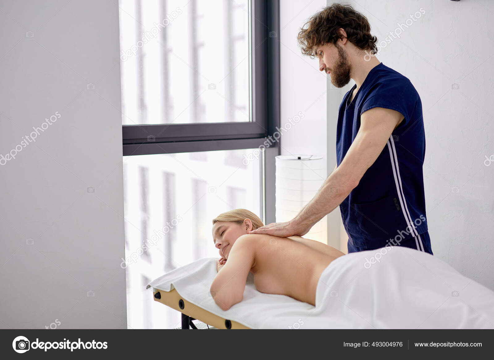 Professional male masseur massages neck and shoulders of young woman in  massage parlor., Stock image