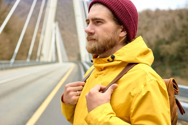 Muž cestovatel chůze na asfaltové cestě na mostě se chystá prozkoumat divoké prostředí — Stock fotografie