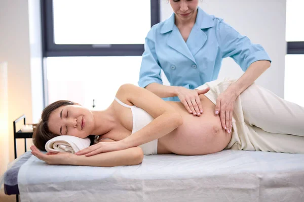 按摩师在温泉沙龙为孕妇按摩肚子。美容术概念. — 图库照片
