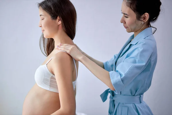 Adorable asiática embarazada hembra consiguiendo spa masaje en la espalda, abrazando la panza — Foto de Stock