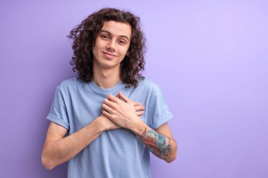 Kıvırcık saçlı yakışıklı adam ellerini göğsüne koy, erkek her şey için minnettar.