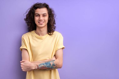 Sakin gülümseyen erkek, kollarını kavuşturmuş, kameraya özgüvenli bir şekilde bakıyor, boşluğu kopyalıyor.