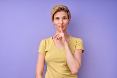 Kafkasyalı sessiz bir kadının stüdyo çekimi ön parmağını dudakların üzerinde tutar, sessiz hareketler yapar.