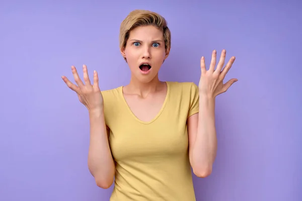 What the fuck. Woman with short hair spreading arms, misunderstanding isolated on purple —  Fotos de Stock