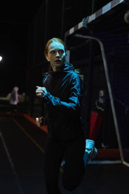 Gece koşusu, koşu, spor kıyafetleri içinde ciddi kızıl saçlı kadın.
