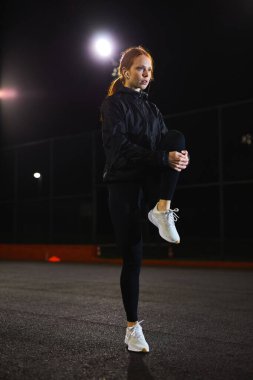 Sıska genç bir kadın geceleri şehir sokağında egzersiz yapıyor..