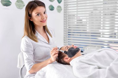 Kafkas kozmetik uzmanı kadın müşteri yüzüne siyah maske takıyor.