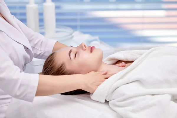 Mujer joven disfrutando de masaje facial anti envejecimiento. Bonita dama consiguiendo cuidado profesional de la piel — Foto de Stock