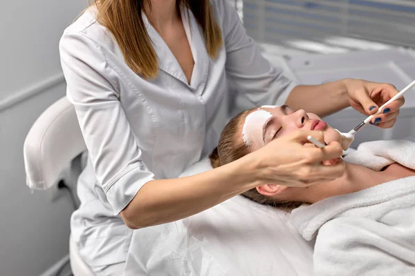 Beautiful young client at beautician getting spa procedures, facial massage and mask — Stock Photo, Image