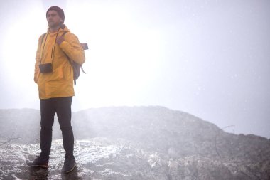 Yürüyüşçü dağların zirvesinde yürüyor sisli ve sisli sabahı seyrediyor