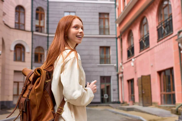 Glad rödhårig kvinnlig turist i rock stående på gatan i gamla stan och skytte på kameran — Stockfoto