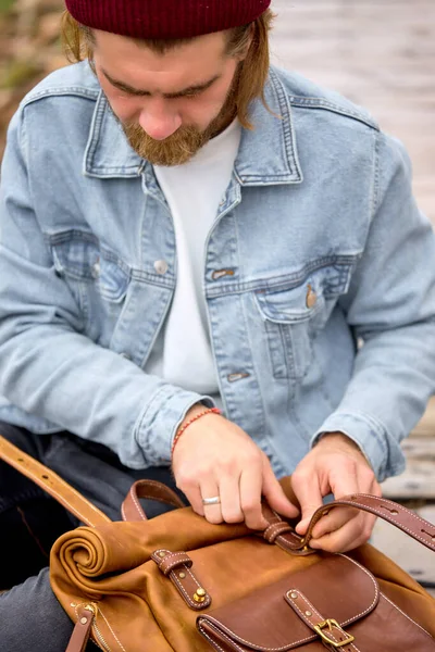 Közelkép a szakállas felfedező férfi kezében barna kézzel készített hátizsák retro stílusban — Stock Fotó