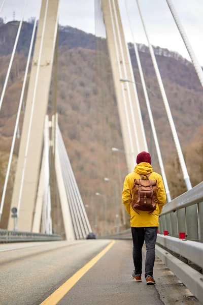 Cestovatel kráčející po asfaltové cestě na mostě se chystá prozkoumat divoké prostředí, zadní pohled — Stock fotografie