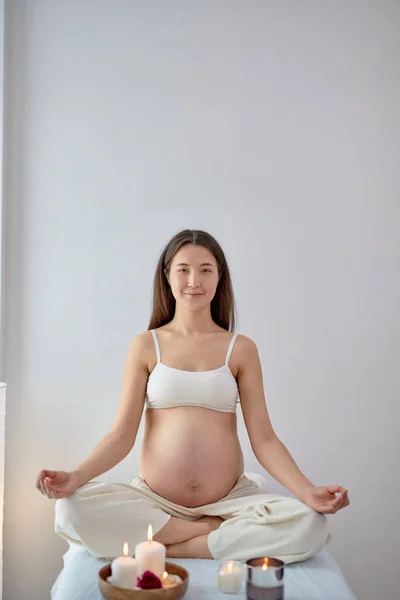 Wanita hamil muda yang menarik duduk di posisi yoga di ruang spa, santai — Stok Foto