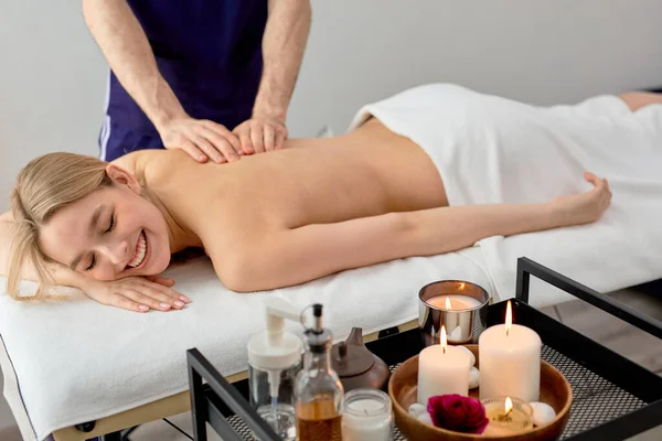 Massagista do sexo masculino massageando costas e omoplatas de fêmea deitada na mesa de massagem no spa — Fotografia de Stock