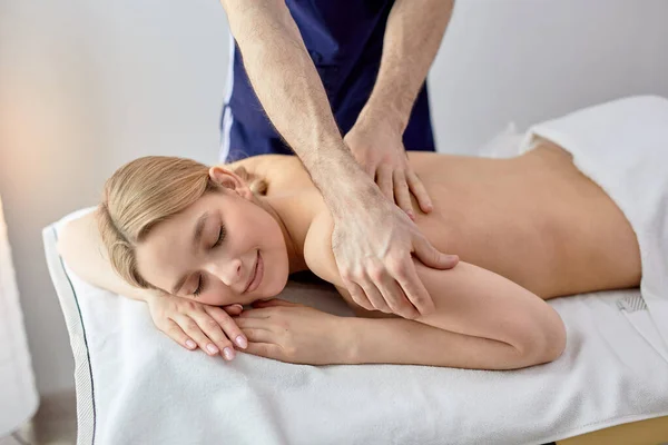 Ung blond kvinna som får ryggmassage från beskuren manlig massör i spa-center — Stockfoto