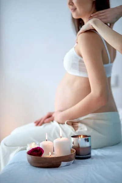 Zwangere vrouw ontvangt terug massage van masseur in spa kabinet, zitten met kaarsen — Stockfoto