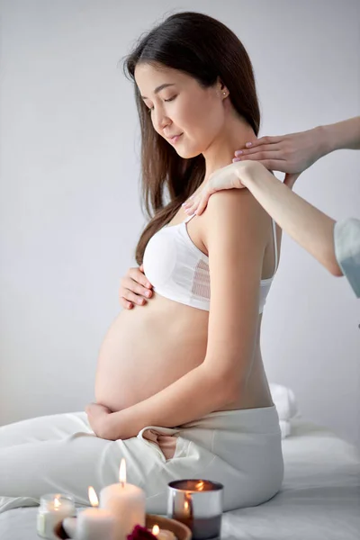 Adorable chino embarazada hembra recibiendo masaje de spa en la espalda, abrazando la panza — Foto de Stock