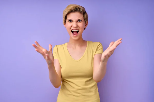 Frau schreit isoliert im Studio auf violettem Hintergrund, Frau breitet Arme aus, irritiert — Stockfoto