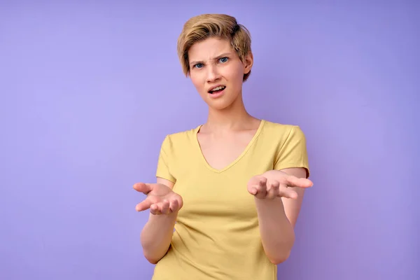 Confuso giovane donna dai capelli corti in maglietta casual mani diffusione con shock — Foto Stock