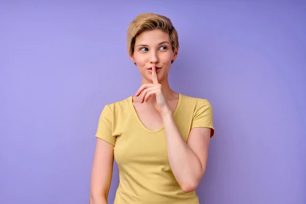 Studio shot van rustige jonge blanke vrouw houdt voorvinger over lippen, stilte gebaar — Stockfoto