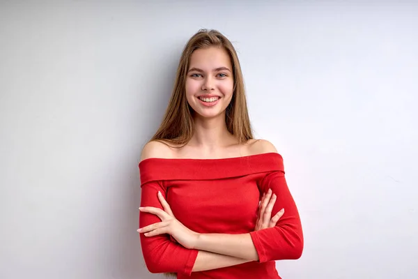 Bella femmina caucasica in camicia rossa posa davanti alla macchina fotografica con le braccia incrociate, giovane donna isolata — Foto Stock