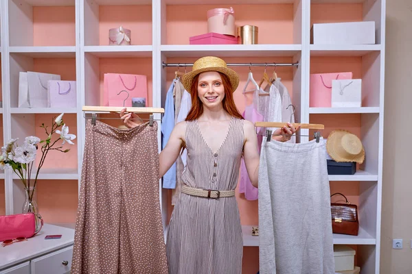 Fashion Closet Concept. Happy stylish female in hat choosing designer clothing on hangers — Stock Photo, Image