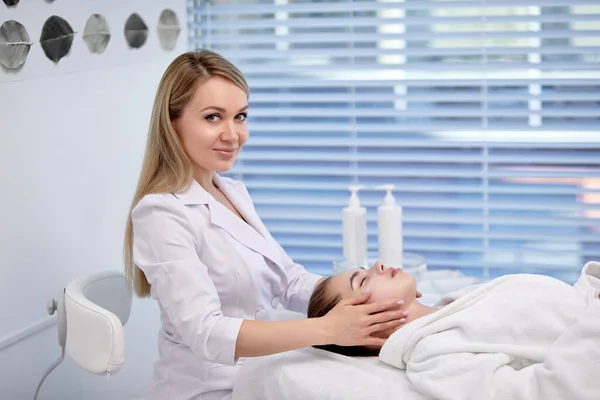 Vista lateral de la esteticista femenina profesional Masajear cara de mujer — Foto de Stock