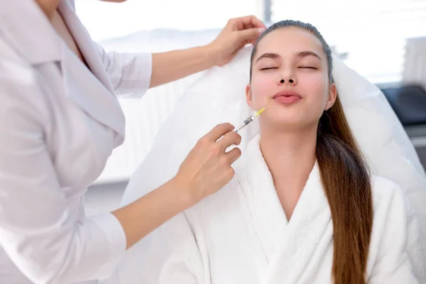 Weibchen mit schöner, sauberer Haut. Kosmetikerin macht Spritzen zur Lippenvergrößerung — Stockfoto