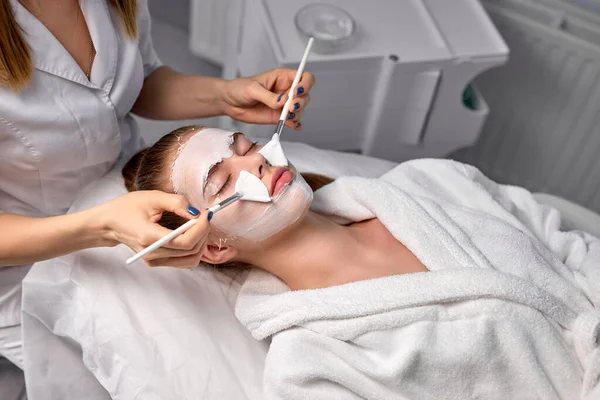 Mujer cosmetóloga cosmetóloga o dermatóloga haciendo mascarilla en el consultorio de cosmetología —  Fotos de Stock