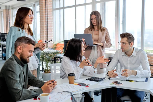 Junge Leute arbeiten als Team im Büro, diskutieren Businesspläne und Strategien, tauschen Ideen aus — Stockfoto