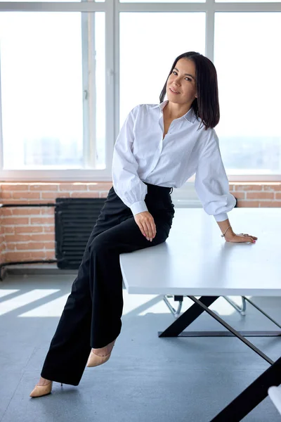 Portrait Of Young Caucasian Brunette Female In Formal Clothes Sitting On Office Desk Table — 스톡 사진