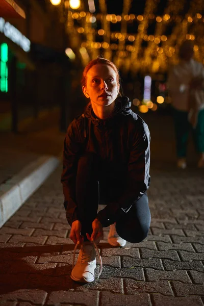 Linda pelirroja hembra ata los cordones en zapatillas deportivas, preparándose para correr — Foto de Stock