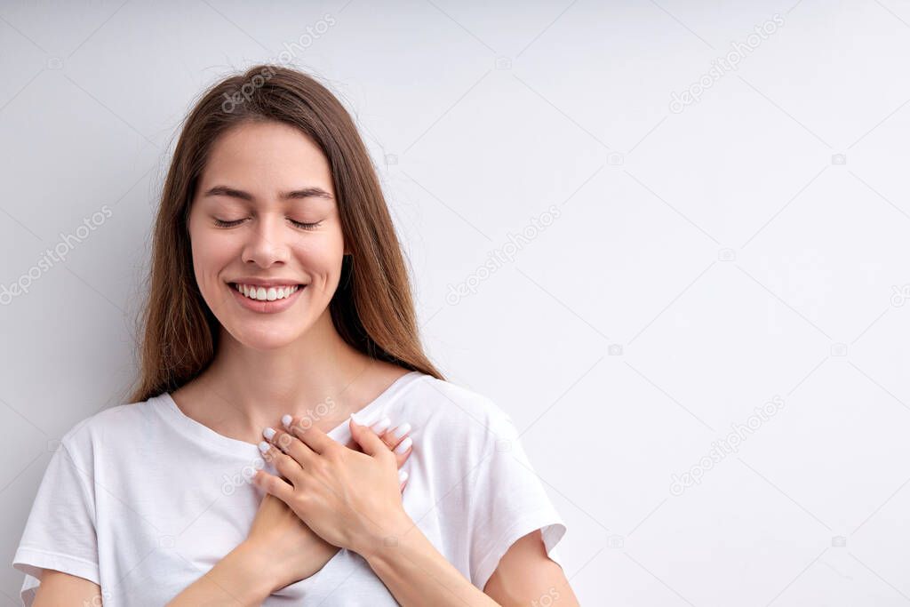 Pretty happy woman expressing gratitude, holding hands on chest, thankful