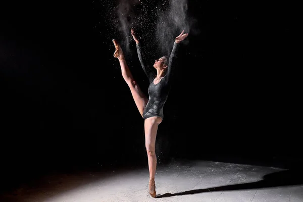 Flexível bailarina mulher dançando e polvilhar farinha no fundo do estúdio preto — Fotografia de Stock