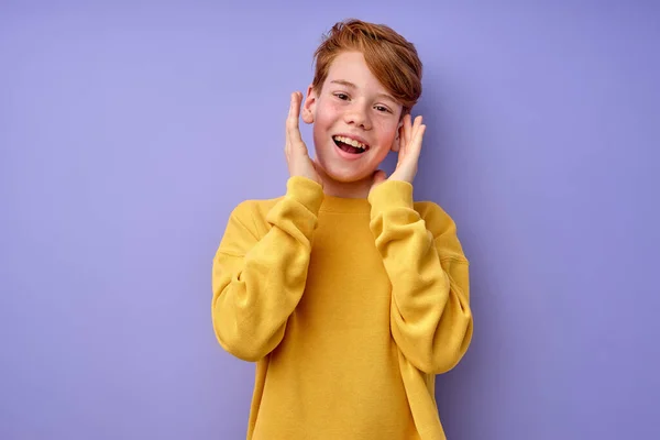 Rödhårig pojke med vidöppna ögon är förvånad, hålla händerna på ansiktet, chock koncept — Stockfoto