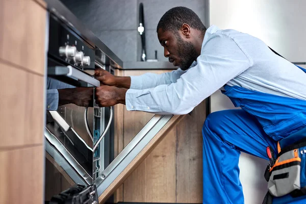 Профессиональный работник по ремонту посудомоечной машины, нужно заменить старый шланг посудомоечной машины — стоковое фото