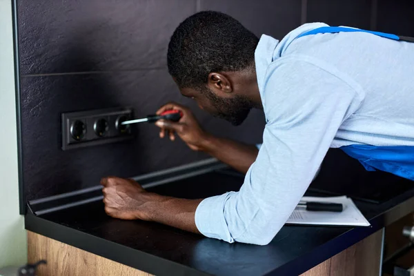 Zelfverzekerde Afrikaanse elektricien, reparaties, installeert stopcontact in de keuken. Man meester — Stockfoto